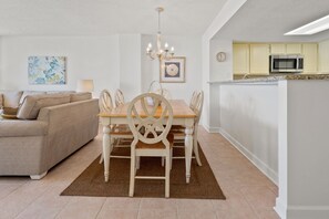 Un salon moderne avec un canapé beige, une table à manger en bois et des chaises. Un lustre est suspendu au-dessus de la table.