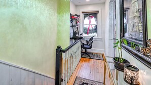 A staircase with a wooden finish, a chandelier, and a window with a view of the Eiffel Tower. - Welcoming Glen Cove Home ~ 1 Mi to Public Beach! (Glen Cove)
