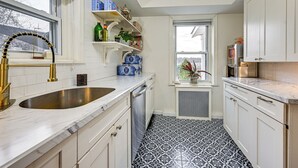 A kitchen with white cabinets, a double sink, and patterned floor tiles. - Welcoming Glen Cove Home ~ 1 Mi to Public Beach! (Glen Cove)