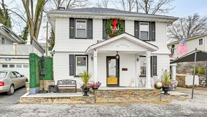 A two-story white house with black shutters, a front porch, and a wreath above the door. - Welcoming Glen Cove Home ~ 1 Mi to Public Beach! (Glen Cove)