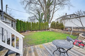 A backyard with a wooden deck, a lawn, and a lawnmower. - Welcoming Glen Cove Home ~ 1 Mi to Public Beach! (Glen Cove)