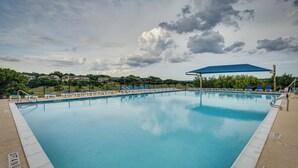 Piscina rectangular con una cubierta azul, rodeada de sillones de descanso y una valla.
