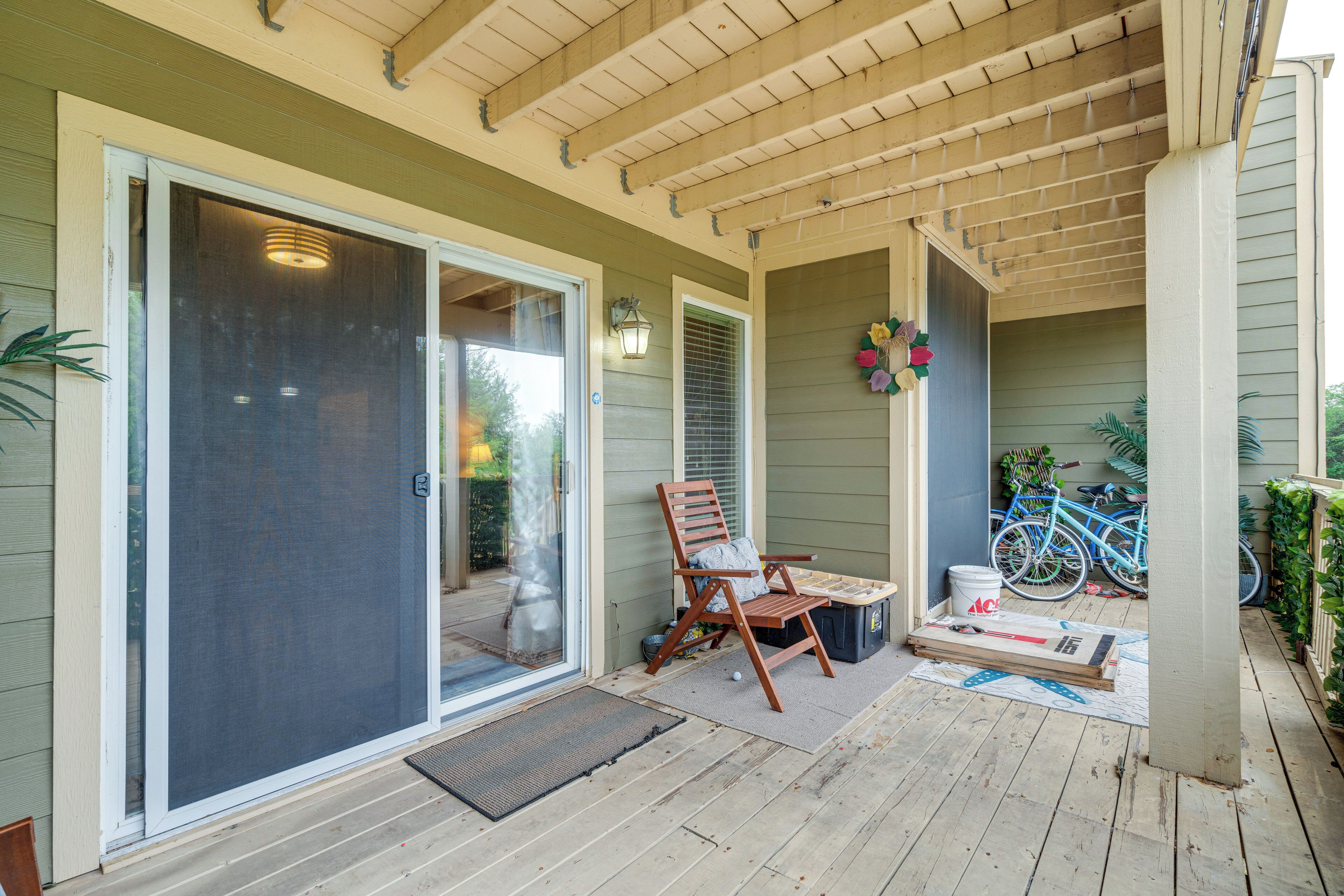 A covered porch with a sliding glass door, a wooden chair, a table, and a bicycle parked nearby.