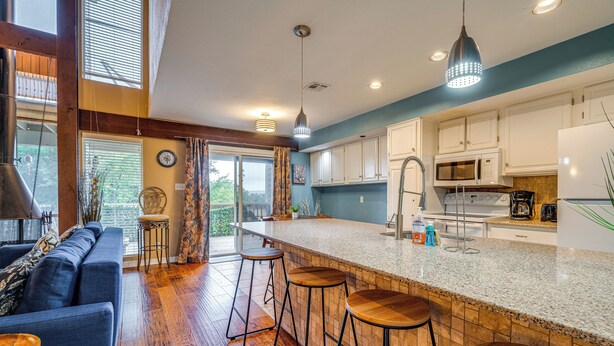 Una cocina moderna con barra, suelo de madera y una pared azul de acento.