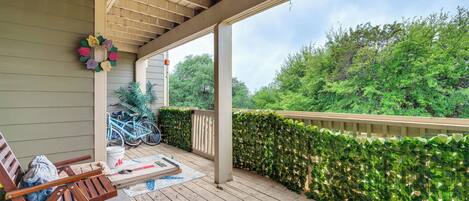 A wooden deck with a pergola, a table with a magazine, and a bench.