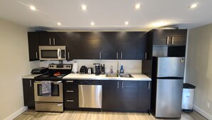 A modern kitchen with dark cabinets, stainless steel appliances, and a white countertop.