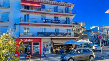 Un hotel de varios pisos con balcones y un toldo rojo.