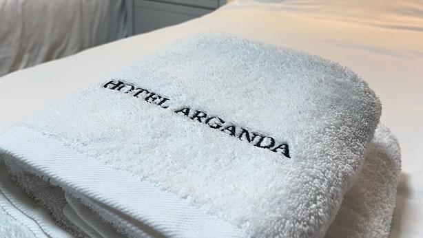 A hotel room with two beds, a nightstand, and a wall-mounted light fixture. - HOTEL ARGANDA (Arganda del Rey)