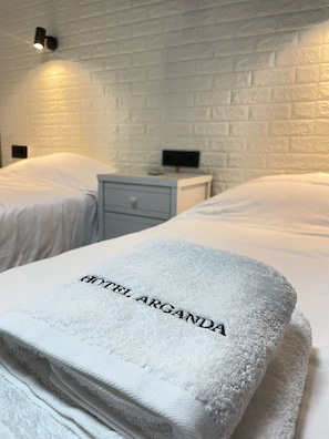 A hotel room with two beds, a nightstand, and a wall-mounted light fixture. - HOTEL ARGANDA (Arganda del Rey)