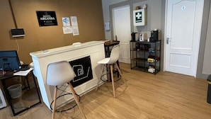 A hotel reception area with a reception desk, two white chairs, a computer, and a wall-mounted sign indicating WiFi availability. - HOTEL ARGANDA (Arganda del Rey)
