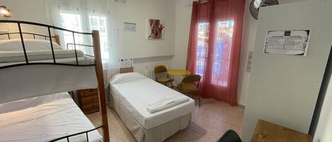 Un dormitorio con literas, una cama individual, una mesita y una silla.
