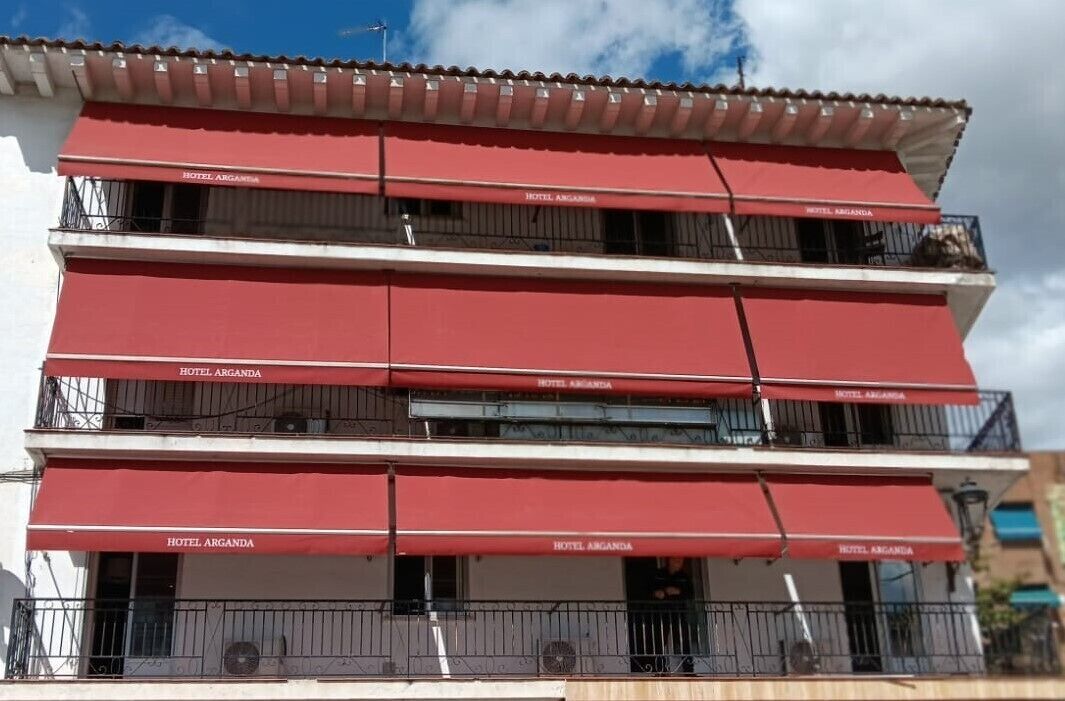 Een hotel met meerdere verdiepingen, rode luifels en balkons.