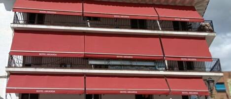Een hotel met meerdere verdiepingen, rode luifels en balkons.