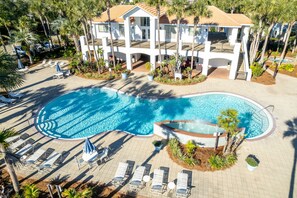 Un resort con una piscina grande, tumbonas y palmeras.