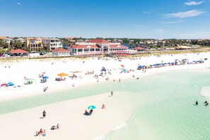 Une plage avec une eau turquoise et limpide, un rivage sablonneux et plusieurs parasols de plage.
