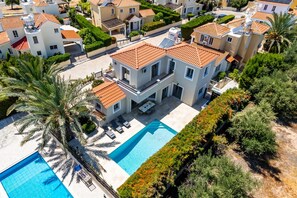 A modern residential complex with multiple two-story houses, a swimming pool, and lush landscaping.