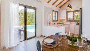 A modern kitchen with a dining area, large windows, and a view of a pool. - Villa Sophia by Ezoria Villas (Paphos)