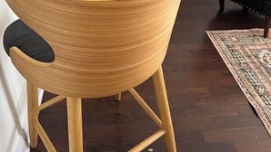 Eine moderne Küche mit Bar, einem Esstisch mit Stühlen, einem schwarzen Ledersessel und einem gemusterten Teppich.