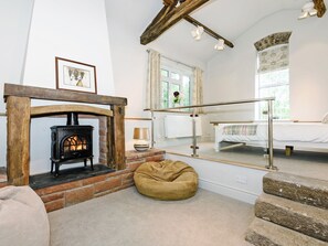 A room with a fireplace, a bed, a window with curtains, and a staircase.
