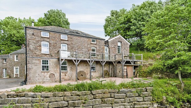 A stone building with multiple windows and a wooden deck. - 4 bedroom accommodation in Great Strickland near Ullswater (Great Strickland near Penrith)