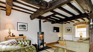 A cozy living room with a fireplace, leather sofas, a television, and artwork on the walls. - 4 bedroom accommodation in Great Strickland near Ullswater (Great Strickland near Penrith)