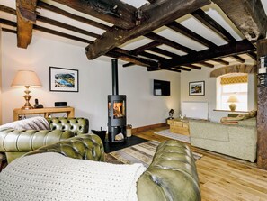 A cozy living room with a fireplace, leather sofas, a television, and artwork on the walls.