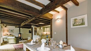 A dining area with a long table set for six, wooden beams on the ceiling, a kitchen in the background, and a framed picture on the wall. - 4 bedroom accommodation in Great Strickland near Ullswater (Great Strickland near Penrith)