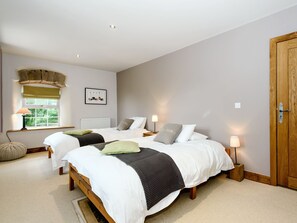 A bedroom with two beds, a window with a view, a radiator, and a wooden wardrobe. - 4 bedroom accommodation in Great Strickland near Ullswater (Great Strickland near Penrith)