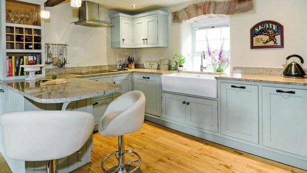 A kitchen with a large island, white bar stools, wooden beams, and a window with a view. - 4 bedroom accommodation in Great Strickland near Ullswater (Great Strickland near Penrith)