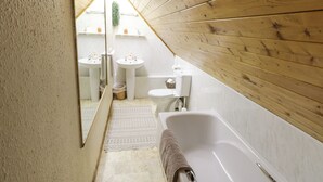 Une petite salle de bain avec un plafond en bois, deux lavabos, des toilettes et une baignoire.