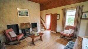 Un salon chaleureux avec une cheminée, des meubles en bois et un escalier menant à une autre pièce.