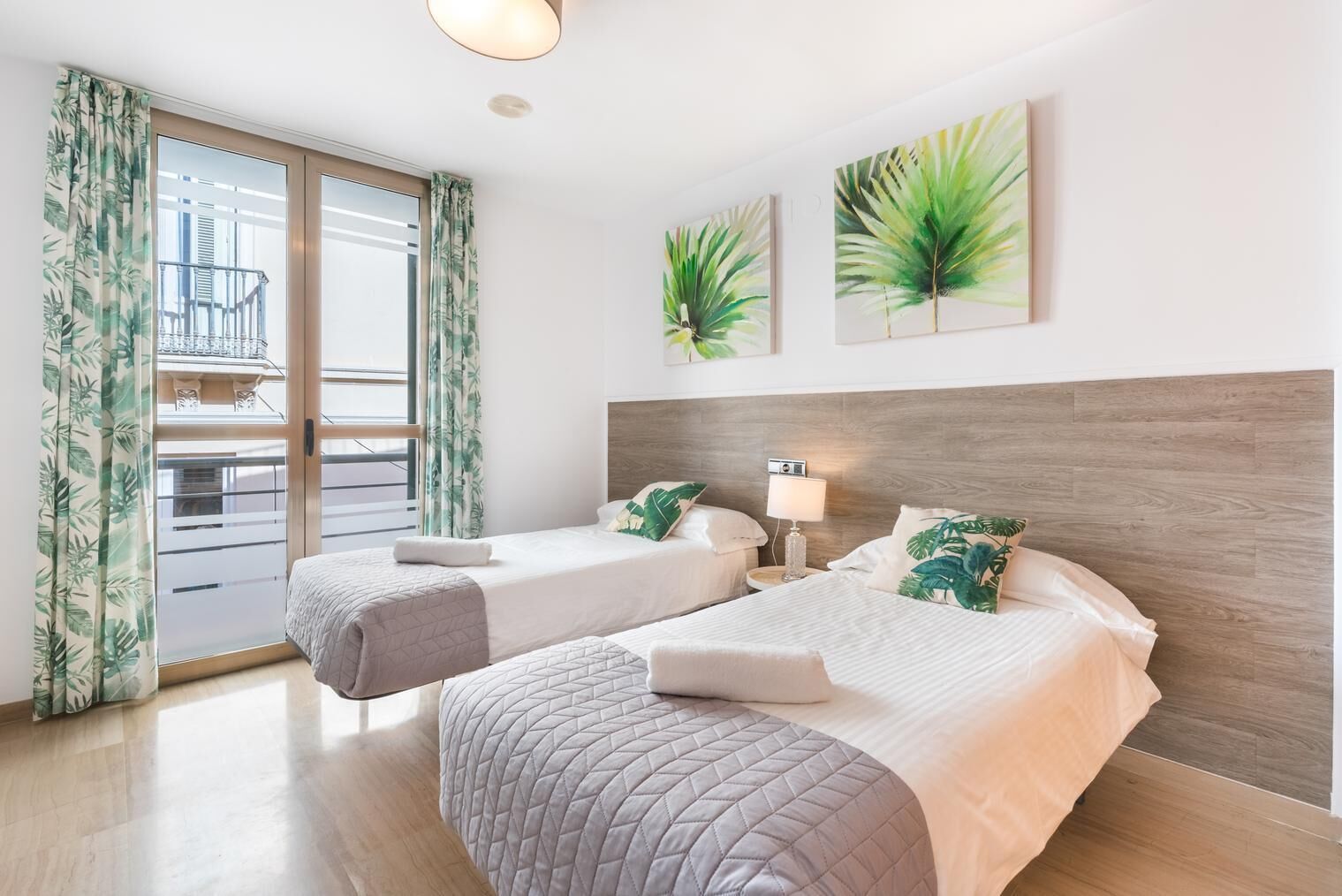 Ein Hotelzimmer mit zwei Betten, einem Balkon und tropischer Einrichtung.