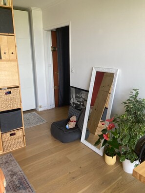 Relax in this serene space with a comfortable bean bag chair, wooden floor, and lush greenery.