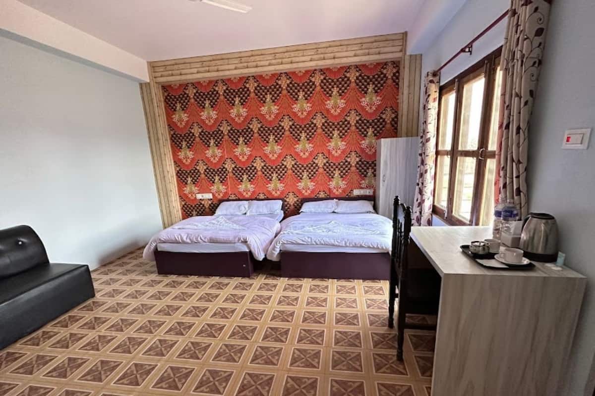 Habitación de hotel con dos camas, un escritorio con hervidor y un sofá.