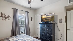 A bedroom with a bed, a dresser, a television, and a window with curtains. - 2BR Sleeps 6 with Balcony, Recliner & Keurig for Your Morning Brew! (Pigeon Forge)