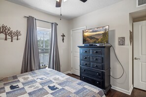 A bedroom with a bed, a dresser, a television, and a window with curtains. - 2BR Sleeps 6 with Balcony, Recliner & Keurig for Your Morning Brew! (Pigeon Forge)