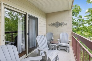 En inglasad veranda med Adirondack-stolar, ett litet bord och en dekorativ väggdekoration.