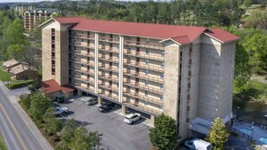 A multi-story hotel with a parking lot and a swimming pool. - Top-Floor Riverfront – 3BR Condo with Elevator Access & Double Vanities (Pigeon Forge)