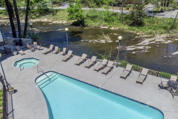 A swimming pool with lounge chairs and a view of a river.