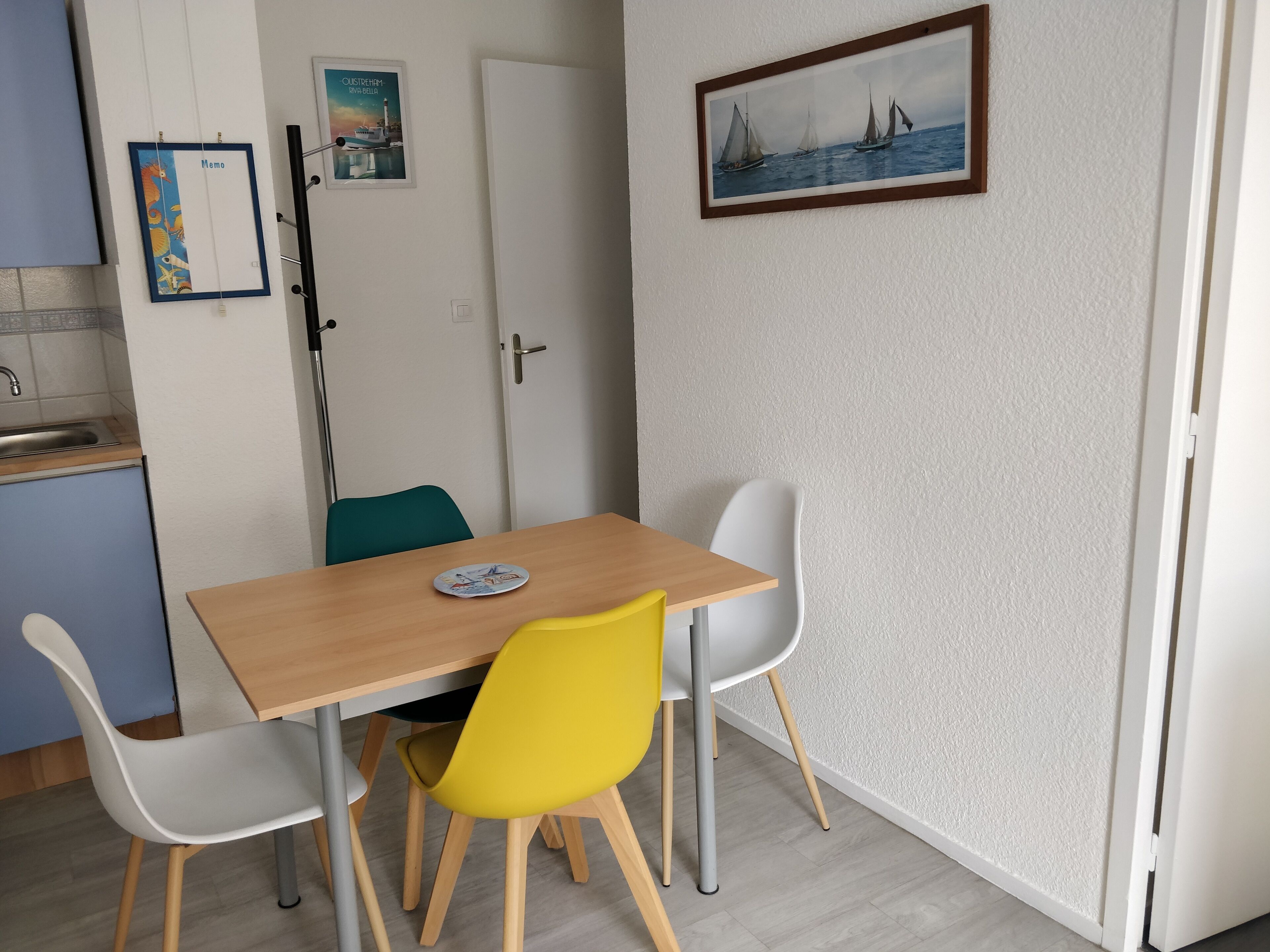 A small dining area with a wooden table and two chairs, one yellow and one white.