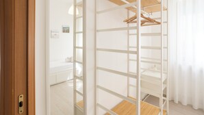 A room with a wooden wardrobe, a mirror, and a hanging rack.