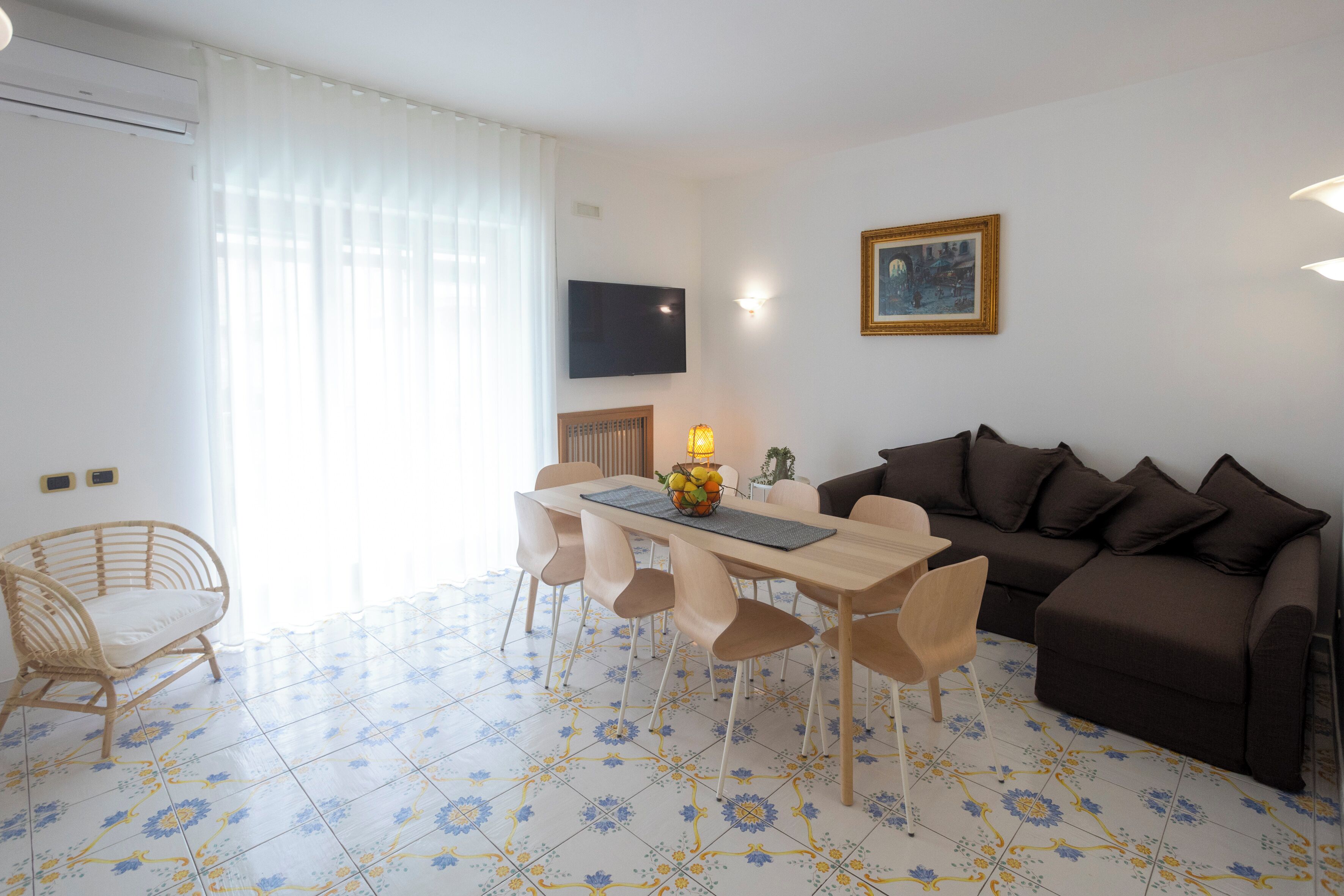 Un salon moderne comprenant une table à manger, des chaises, un canapé et un téléviseur fixé au mur.