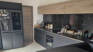 Una cocina moderna con encimera negra, electrodomésticos de acero inoxidable y salpicadero de mármol.