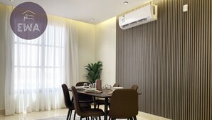 A dining area with a table set for four, chairs, a potted plant, and an air conditioning unit mounted on the wall. - Kease Qirwan B-11 Royal touch  XZ13 (Riyadh)