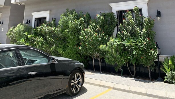 A multi-story building with balconies, a sign indicating room number B, and a car parked in front. - Kease Qirwan B-11 Royal touch  XZ13 (Riyadh)