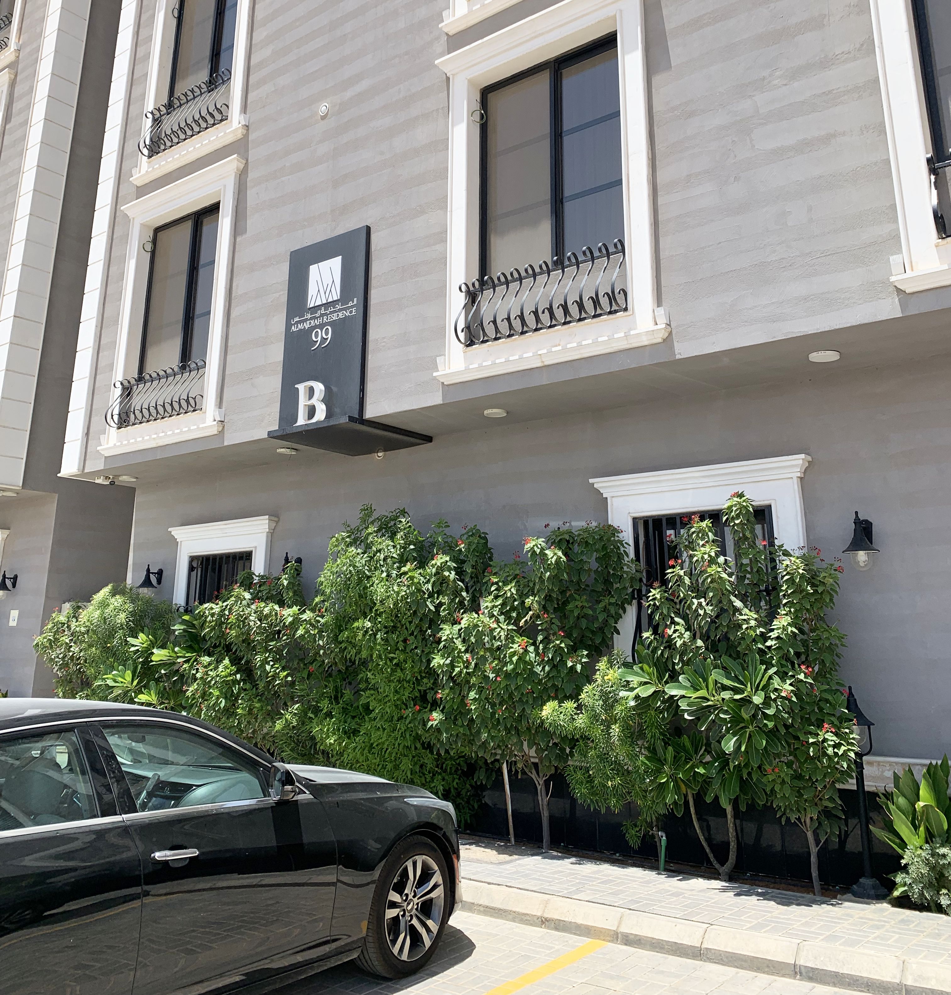 Un edificio a più piani con balconi, un cartello che indica la camera B e un'auto parcheggiata davanti.