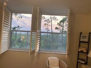 Una habitación con un ventanal grande, una silla y una estantería.