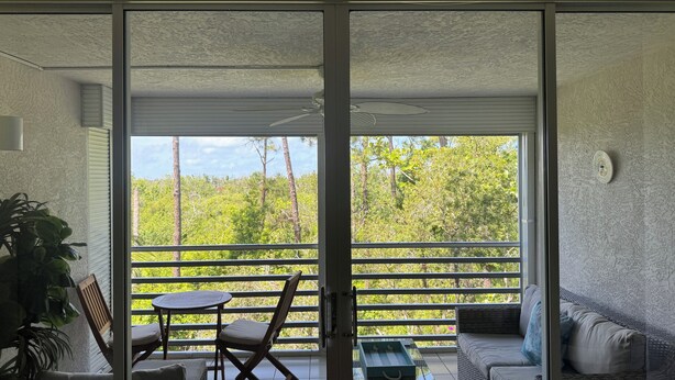 Un balcon agrémenté d’une table, de chaises et d’un canapé, offrant une vue sur un paysage verdoyant et luxuriant.
