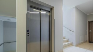 En modern hiss med en metallisk yta, ett handräcke och en kontrollpanel med knappar.