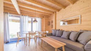 Un intérieur en bois comprenant un canapé, une table à manger, des chaises et un luminaire suspendu.